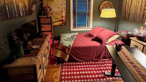 A bedroom with a bed, a desk, a chair, a standing lamp, a ceiling fan, and artwork on the walls. - Spacious Craftsman Guest Suite in VA-Highland (Atlanta)