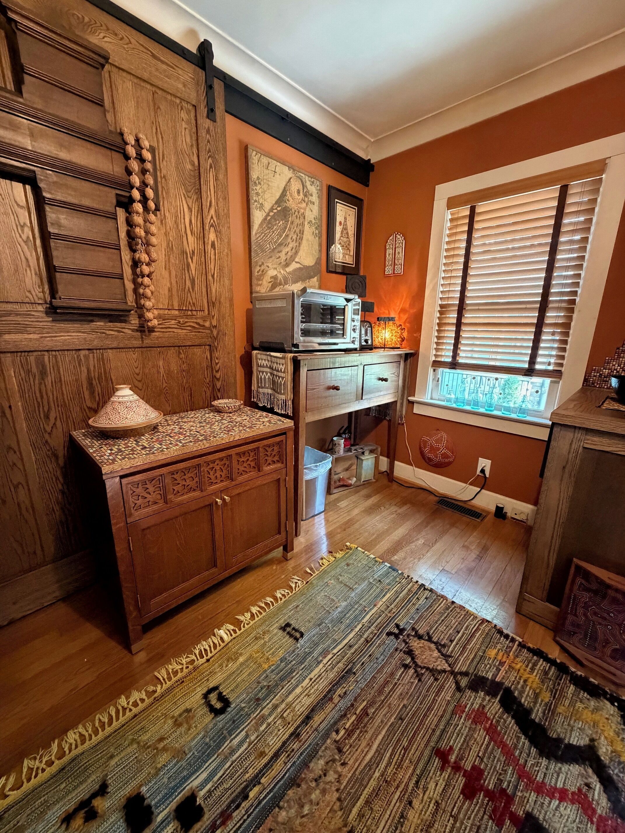A kitchen with wooden cabinetry, a microwave, and a patterned rug.