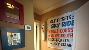 A hallway with a wall-mounted sign advertising sky ride tickets, a framed picture, and a door. - Spacious Craftsman Guest Suite in VA-Highland (Atlanta)