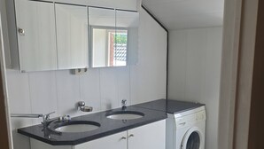 Un baño moderno con lavamanos, espejo y lavadora.