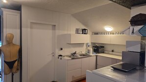 Una cocina con armarios blancos, un lavamanos, una cafetera y una balanza en la encimera.