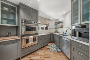 A modern kitchen with grey cabinets, stainless steel appliances, and a wooden floor. - Eagle-Vail Duplex - Golf Front - Near Beaver Creek (Avon)