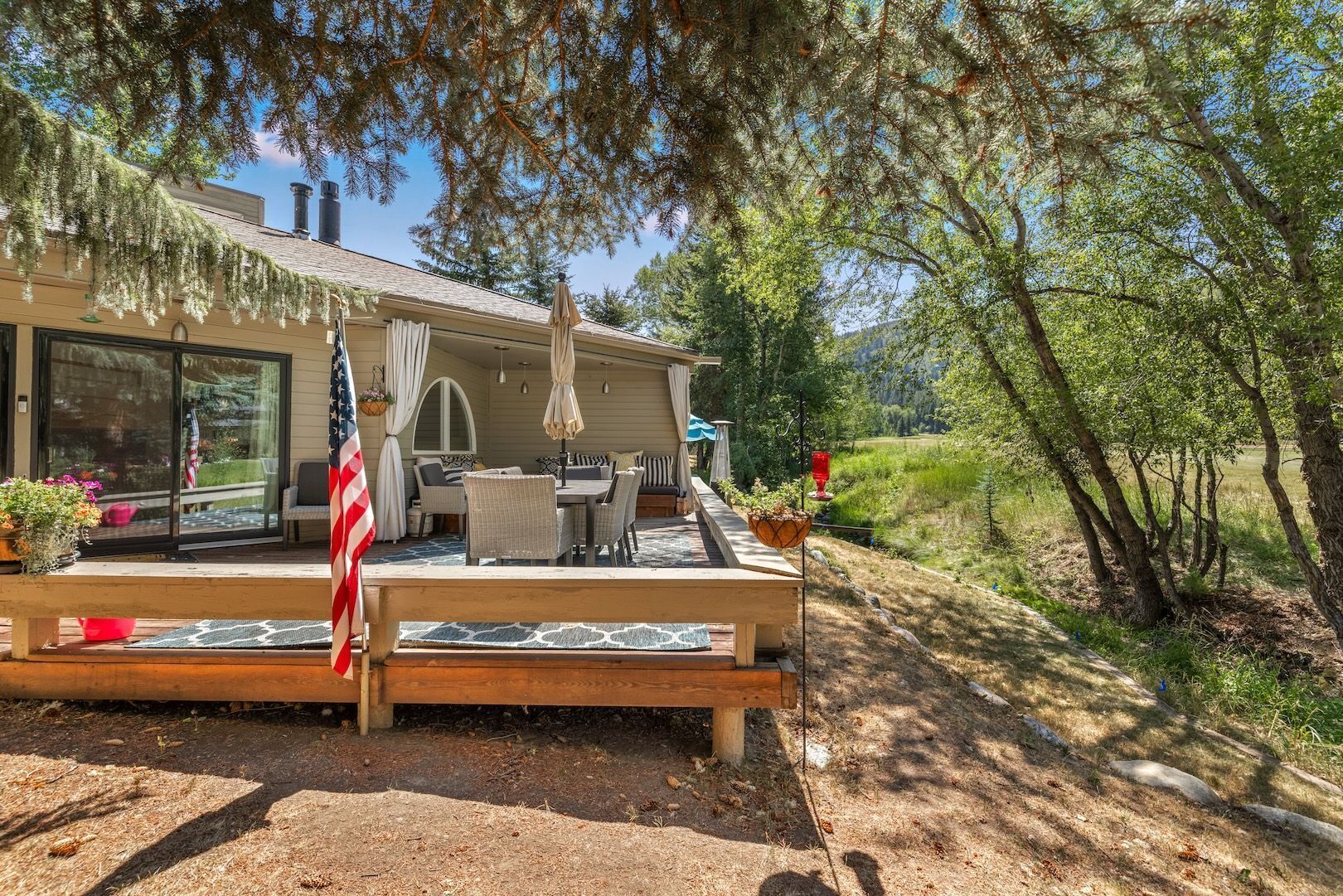 A house with a deck, outdoor furniture, and a flag.