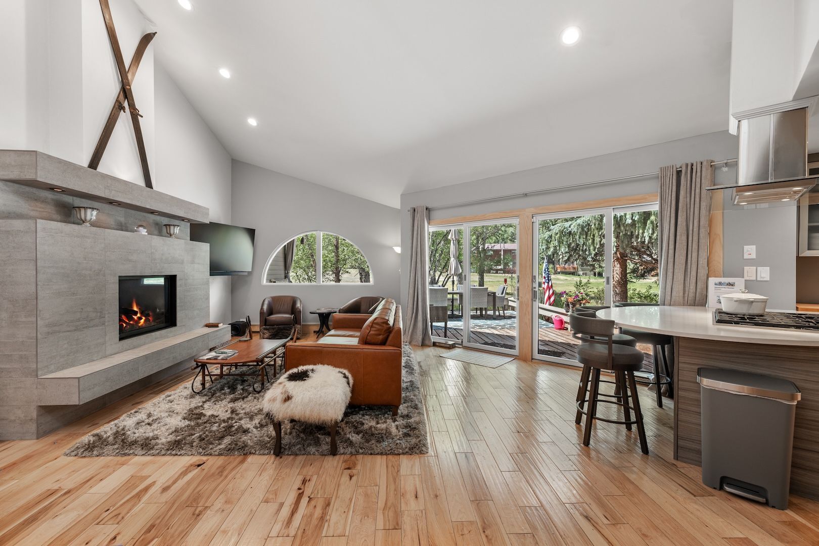 A modern living room with a fireplace, seating area, and a view to the outdoors.