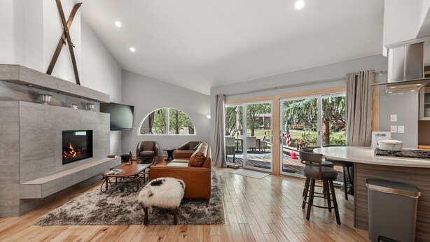 Una sala de estar moderna con chimenea, zona de estar y vistas al exterior.