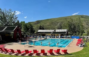A swimming pool with multiple lanes, red lounge chairs, and a red barn-like structure. - Eagle-Vail Duplex - Golf Front - Near Beaver Creek (Avon)