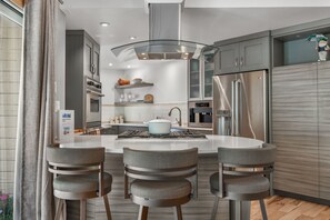 A modern kitchen with a central island, stainless steel appliances, and a seating area with four chairs. - Eagle-Vail Duplex - Golf Front - Near Beaver Creek (Avon)