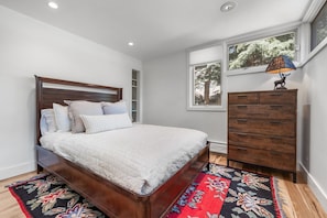 A bedroom with a wooden bed, a dresser, and a window with a view of trees. - Eagle-Vail Duplex - Golf Front - Near Beaver Creek (Avon)