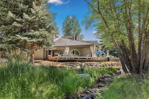 A house with a deck, outdoor furniture, and a small stream. - Eagle-Vail Duplex - Golf Front - Near Beaver Creek (Avon)