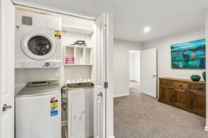 A laundry room with a washing machine, dryer, and ironing board. - Mountain View Marina with Remarkables Backdrop (Queenstown)