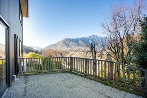 Ein Balkon mit Blick auf Berge, einem Holzzaun und einem Gebäude mit einem Fenster.