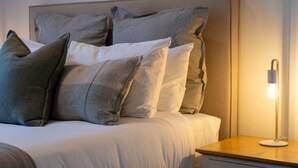 A neatly made bed with multiple pillows and a bedside lamp. - Mountain View Marina with Remarkables Backdrop (Queenstown)