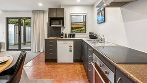 A compact kitchen with a dishwasher, microwave, and a gas stove. - Mountain View Marina with Remarkables Backdrop (Queenstown)