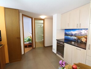 A compact kitchen with a stove, sink, and a painting of a mountain landscape. - GOLF Apartments Appartement/Fewo 2-Bettwohnung Nr. 4 by Interhome (Saas-Fee)