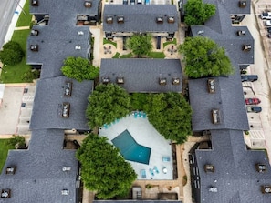 A residential area with multiple houses, a central swimming pool, and surrounding greenery. - 2 Min AT&T Stadium Walk | Cozy & Clean 2BR Apt (Arlington)