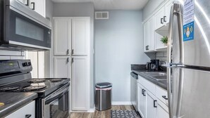 A modern kitchen with stainless steel appliances, white cabinetry, and a patterned rug. - Arlington 2BR | AT&T, Globe Life, 6 Flags, Parking (Arlington)