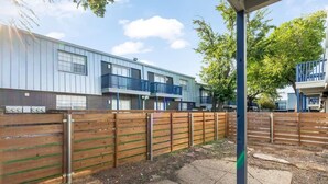 A residential building with a wooden fence, a paved area, and a clear sky. - Arlington 2BR | AT&T, Globe Life, 6 Flags, Parking (Arlington)