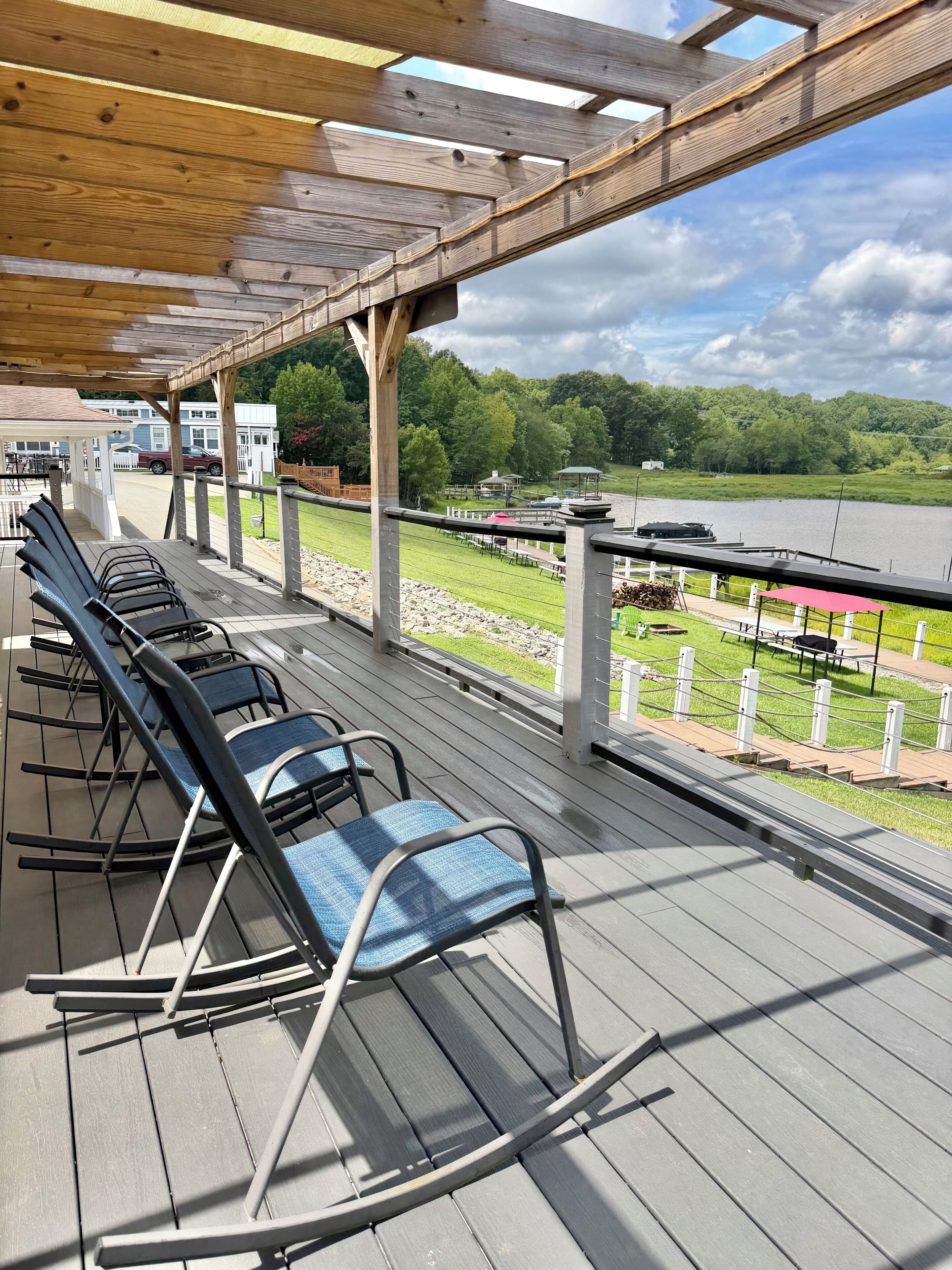Un espace extérieur aménagé, abrité et doté de fauteuils confortables, offrant une vue sur un lac et la verdure environnante.