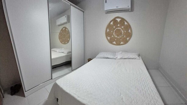 Un dormitorio con cama, armario, espejo y aire acondicionado instalado en la pared.