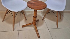 Una mesa redonda de madera con dos sillas blancas a cada lado.