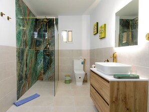 Ein Badezimmer mit einer Duschkabine, einem weißen Waschbecken und einem Holzwaschtisch.