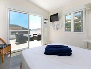 Ein Hotelzimmer mit Bett, Sessel, Fernseher und Balkon mit Blick.