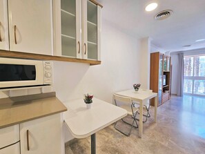 Une cuisine moderne avec des meubles blancs, un four à micro-ondes et une petite table avec des chaises.