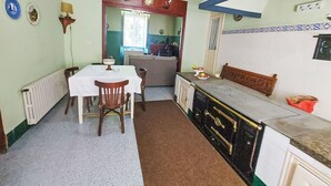 Cuina funcional amb taula de menjador, cadirees, fogó i zona de seients.