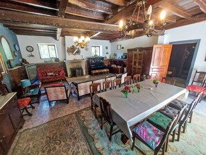 Ein traditionell eingerichteter Raum mit Esstisch, Stühlen, einer Couch, einem Kamin und einem Klavier.