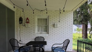 A covered patio with a brick wall, a table with chairs, string lights, and a window. - The Massillon Retreat! (Massillon)