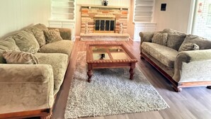 A living room with two sofas, a coffee table, a fireplace, and a window. - The Massillon Retreat! (Massillon)