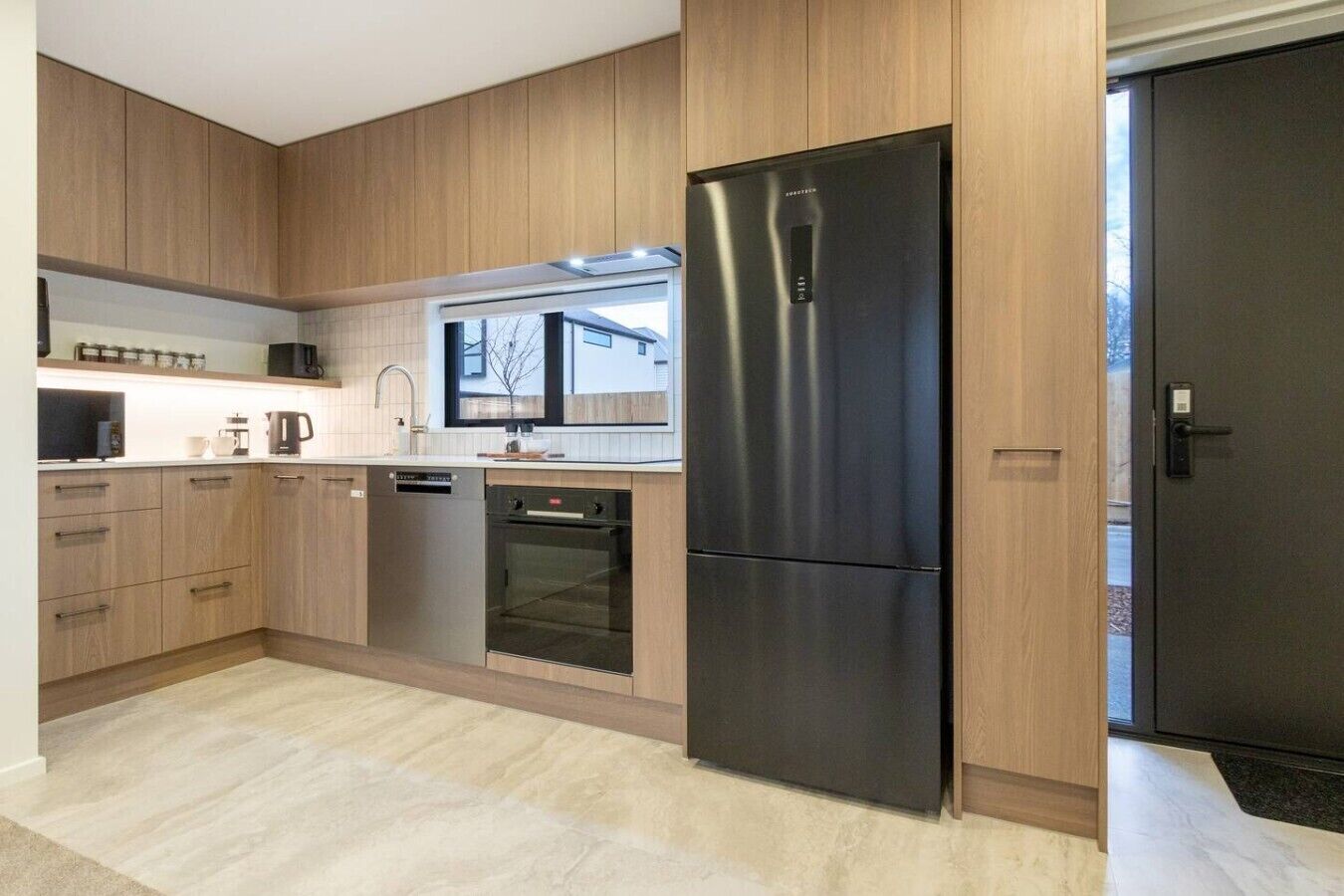A modern kitchen with wooden cabinets, stainless steel appliances, and a black refrigerator.