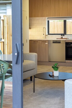Eine moderne Küche mit Holzausstattung, einem eingebauten Backofen und einem Essbereich mit rundem Tisch und Stühlen.