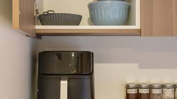 A kitchen with a microwave, a black appliance on the counter, and jars on the shelf.