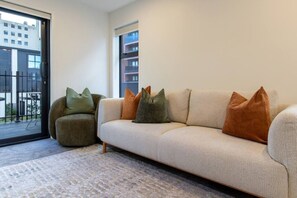 Un salon moderne avec un canapé, un fauteuil et un tapis à motifs.
