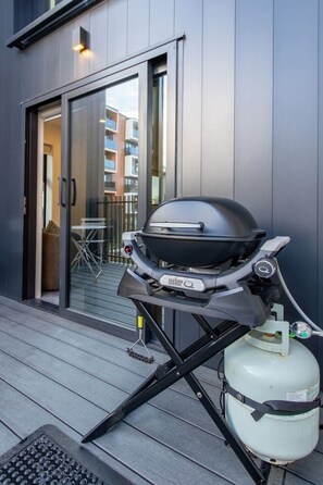 A portable Weber Q grill with a propane tank on a balcony. - Walk Everywhere! CBD Pad + Stadium & Parking (Christchurch)