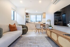 Un salon moderne avec un canapé, une table basse et un téléviseur.