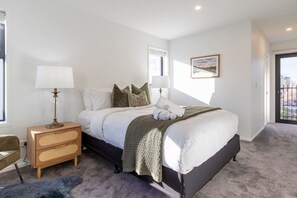 Ein Schlafzimmer mit Bett, Nachttischen, einer Lampe, einem Bild an der Wand und Blick durch das Fenster.