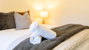 Habitación de hotel con cama, almohadas, manta, lámpara y equipo de aire acondicionado.