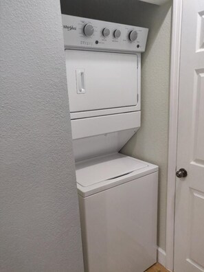 A compact laundry room with a front-loading washer and dryer. - Island Zen: A tranquil 1-bedroom perfect for the solo traveler for work or play! (George Town)