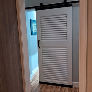 Eine Schiebetür mit Griff, die in einen Raum mit Holzboden und blauer Wand führt.