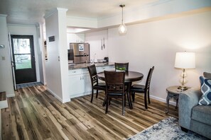 Una cocina moderna con comedor, suelo de madera y vistas al salón.