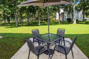 Una mesa de patio con cuatro sillas y un paraguas grande.
