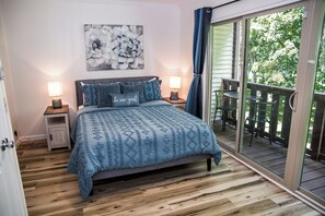 Un dormitorio con cama, lámparas de noche, un reloj y vistas a un balcón exterior.