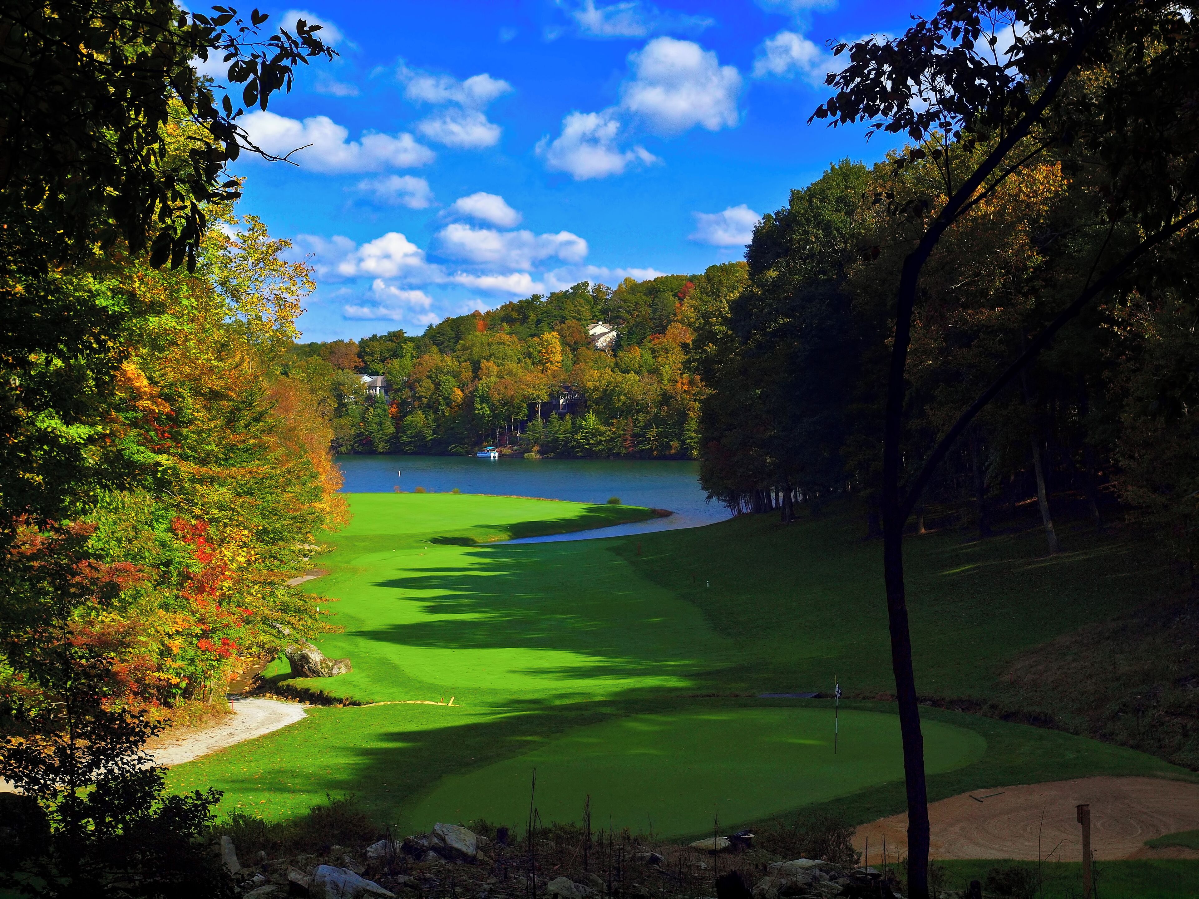 Un parcours de golf avec un lac, entouré d’arbres et de maisons.