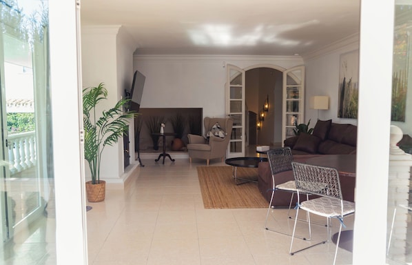 A living room with a sofa, armchair, coffee table, and a potted plant.
