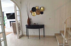 A modern living room with a flat-screen TV, a decorative wall piece, and a 'HOME' sign on a console table.