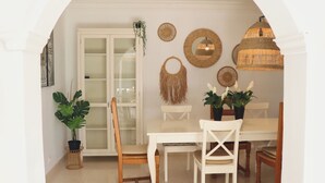 Uma área de refeições com uma mesa branca, cadeiras e um armário de vidro.