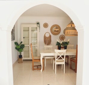 A dining area with a white table, chairs, and a glass cabinet.