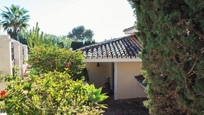 Um imóvel residencial com telhado de telhas, entrada de tijolos e um jardim com diversas plantas e flores.
